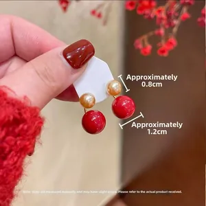 Detail of red and gold pearl earrings with 0.8cm and 1.2cm spheres in hand