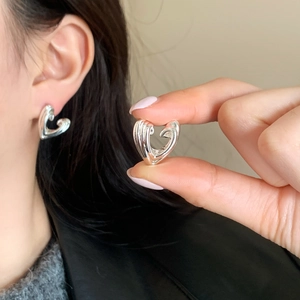 Macro shot of irregular hollow heart stud earrings with a polished silver mirror finish