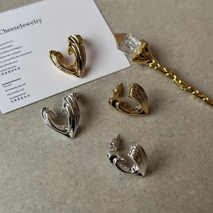 Macro view of gold and silver heart earrings featuring textured wavy vertical patterns