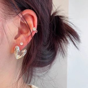 Close-up of heart-shaped silver earrings with unique lava texture on a model's ear