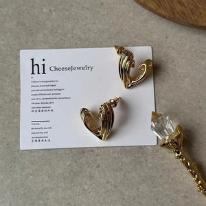 French vintage style gold swirl heart stud earrings displayed on a white jewelry card
