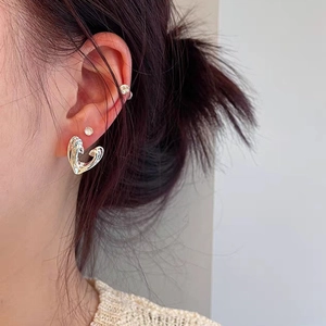 Close-up of model wearing silver heart earrings and small rhinestone studs on ears