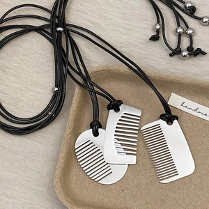 Minimalist silver comb pendant necklaces with black adjustable cord on rustic background
