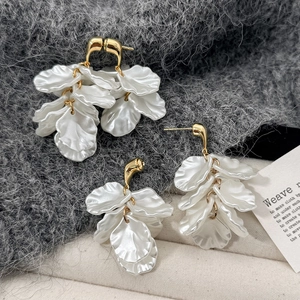 Detail of layered white petal earrings with elegant gold metal ring accents on soft fabric