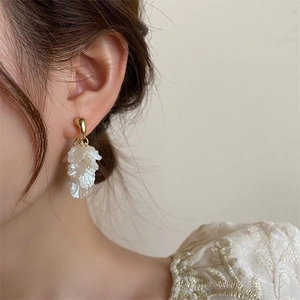 Detail of floral tassel earrings with translucent petals and gold finish on model