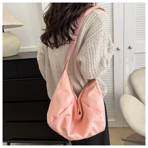 Détail du grand sac à bandoulière rose matelassé porté dans un intérieur cosy