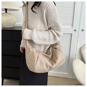 Détail d'un sac bandoulière en nylon beige avec large sangle réglable et boucle en argent