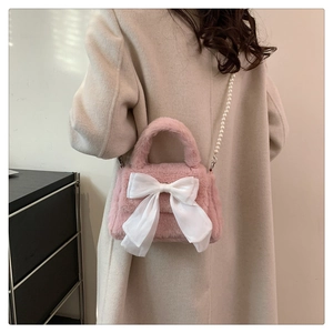 Détail du sac en peluche rose avec un grand nœud en satin blanc et bandoulière en perles