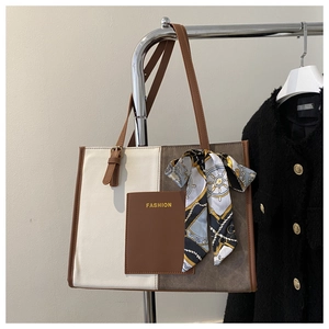 Detail of a brown and white tote bag with silk scarf and FASHION logo on a hanger