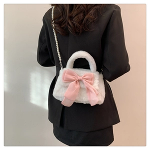 Détail du sac en peluche avec grand nœud rose et bandoulière en perles