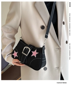 Close-up of black canvas shoulder bag with pink star patches and silver metal buckle