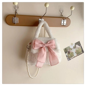 Vue détaillée du sac en peluche blanc avec nœud rose et bandoulière en perles