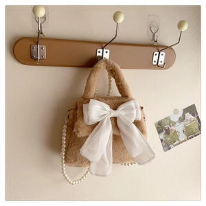 Détail du sac en peluche camel avec nœud en organza blanc et élégante bandoulière perle