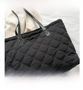 Detail view of large quilted tote bag with diamond stitching and black leather handles