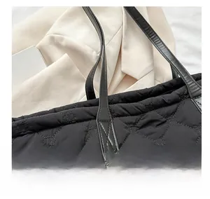 Close-up of black quilted tote bag with rhombus pattern and faux leather strap detail