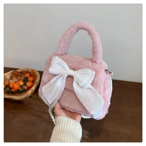 Détail du sac en peluche rose avec un grand nœud en organza blanc et bandoulière perle
