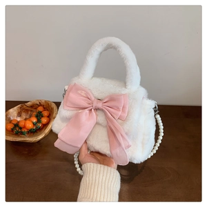 Détail d'un sac en peluche blanc avec un grand nœud rose et une lanière en perles chics