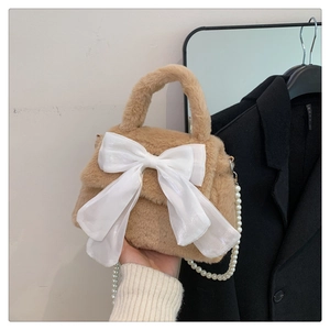 Gros plan d'un sac en peluche kaki avec grand nœud en satin blanc et chaîne en perles