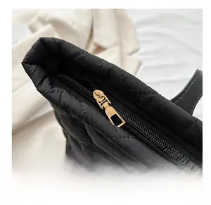 Close-up of golden smooth zipper and black quilted fabric on stylish winter tote bag