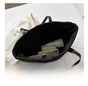 Spacious interior of quilted tote bag holding umbrella, wallet and smartphones