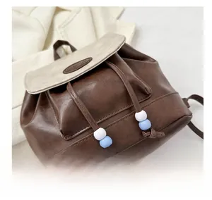 Close-up of retro brown and beige drawstring backpack with blue bead and fashion label