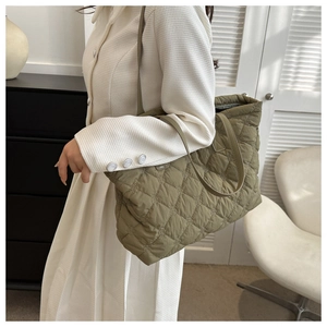Olive green quilted tote bag with diamond stitching shown in a stylish commute lifestyle setting