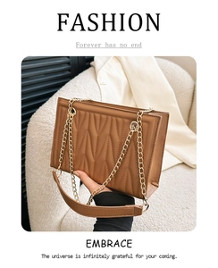Detail of wave-pattern quilted brown leather bag with golden chain and shoulder strap