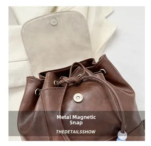 Detail showing magnetic snap closure and drawstring on vintage brown leather backpack