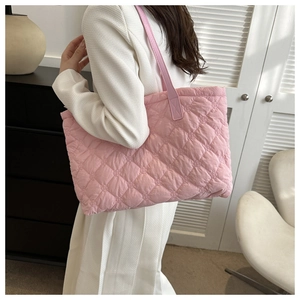 Pink quilted tote bag with diamond stitching shown on a shoulder in a modern room