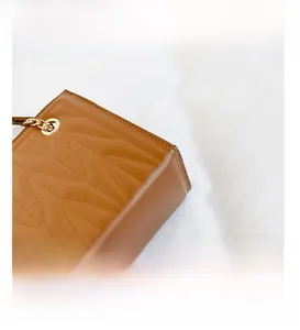 Detail of brown quilted leather handbag with premium gold chain and metal eyelets