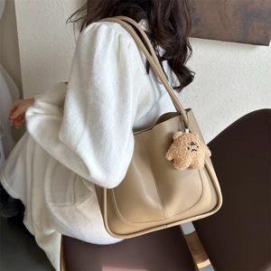 Minimalist khaki leather tote bag with cute teddy bear charm shown on model