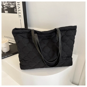 Detail of a black quilted nylon tote bag with rhombus patterns and slim shoulder straps