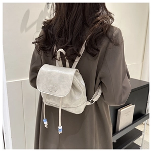 Detail of a mini beige pearl backpack with drawstring and embossed fashion logo