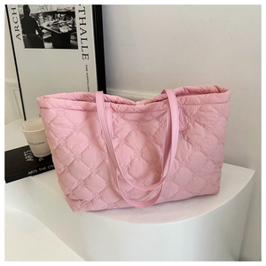 Detailed view of pink quilted tote bag with diamond stitching on a minimalist display
