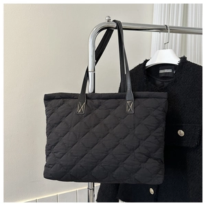 Close-up of black quilted cotton tote bag with diamond stitching and leather straps