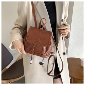 Close-up of retro brown mini leather backpack with fashion embossing and beaded drawstrings