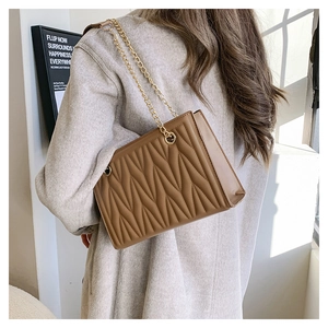 Close-up of brown matelasse quilted bag with golden chain strap on a model