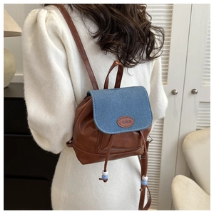 Detail of mini backpack showing brown faux leather and blue denim patchwork with drawstring