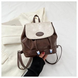 Detailed shot of dark brown mini backpack with drawstring closure and fashion badge