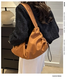 Detailed view of caramel brown pleated tote bag being worn over the shoulder by a model