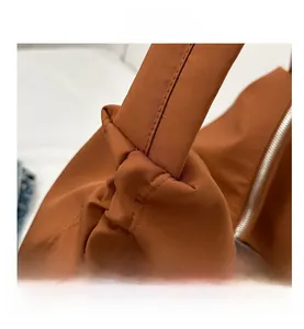 Detail shot of the knotted shoulder strap and silver zipper on this nylon tote bag
