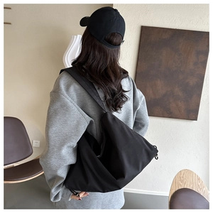 Side view of large black nylon hobo bag showing spacious design and soft texture on model