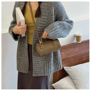Brown Boston bag with letter embossing shown in a cozy home lifestyle setting