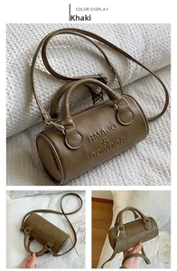 Macro detail of khaki cylinder bag showing leather texture and embossed logo