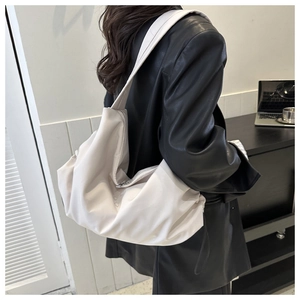 Close-up of beige nylon tote bag with pleated design worn by a model in a modern office