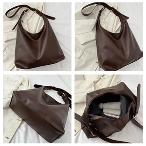 Detail of dark brown leather tote bag with wide adjustable strap and gold metal buckle