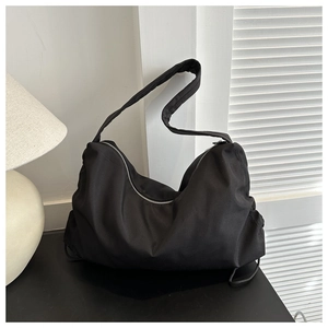 Detail of a large black nylon crescent tote bag with metal zipper and wide shoulder strap