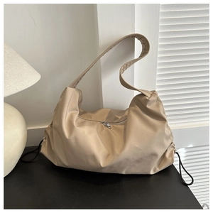 Detail of light khaki nylon hobo bag with silver zipper and black drawstring accents
