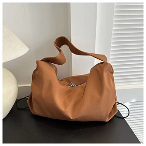 Detail view of large nylon crossbody bag in caramel brown with silver dual zippers