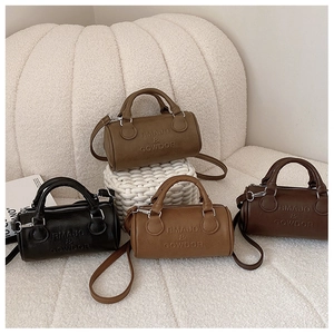 Mini cylindrical leather bags in various earthy tones displayed on a soft textured background